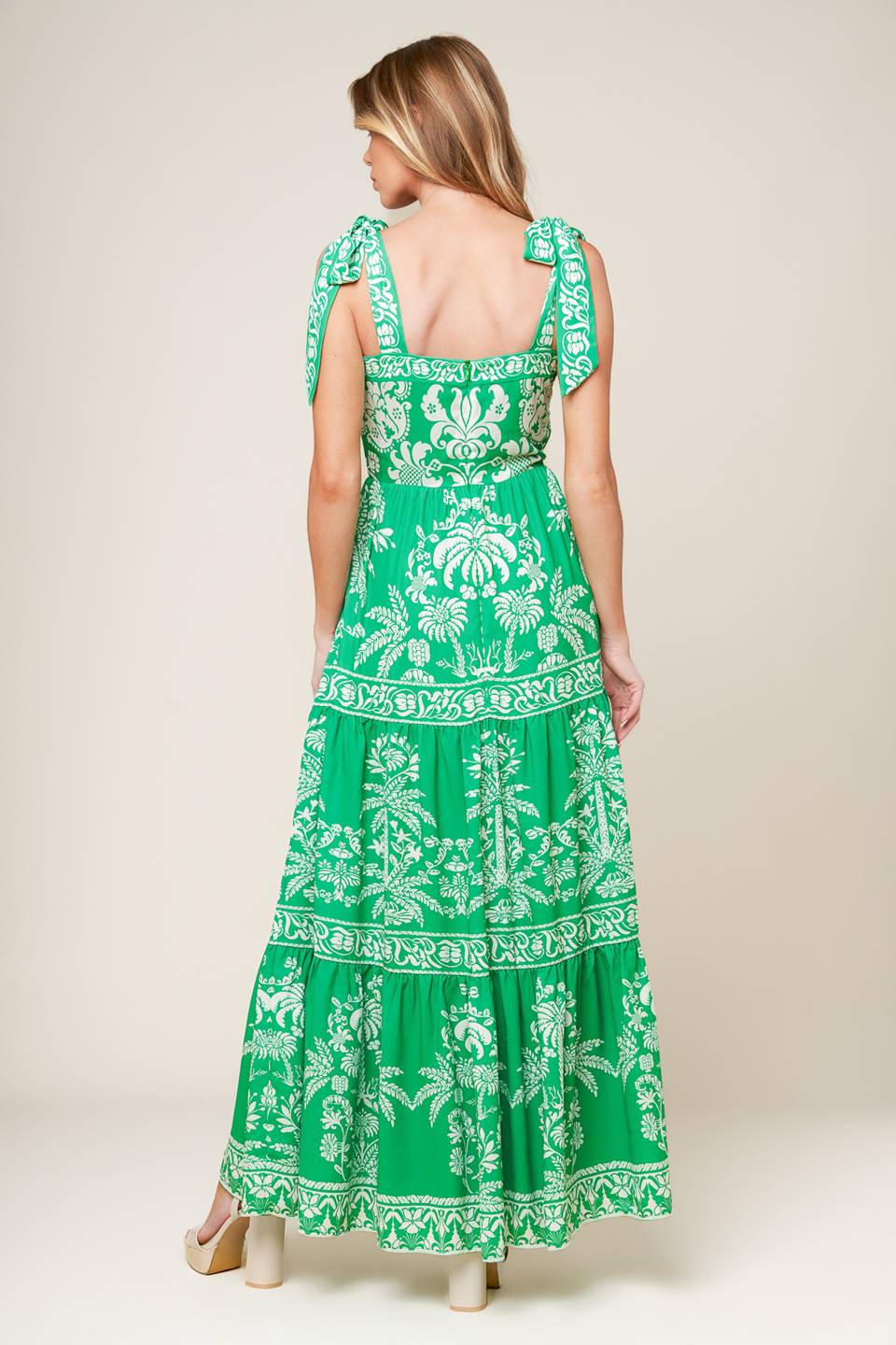 A printed woven maxi dress featuring straight neckline, shoulder ties, tiered skirt and back zipper closure.