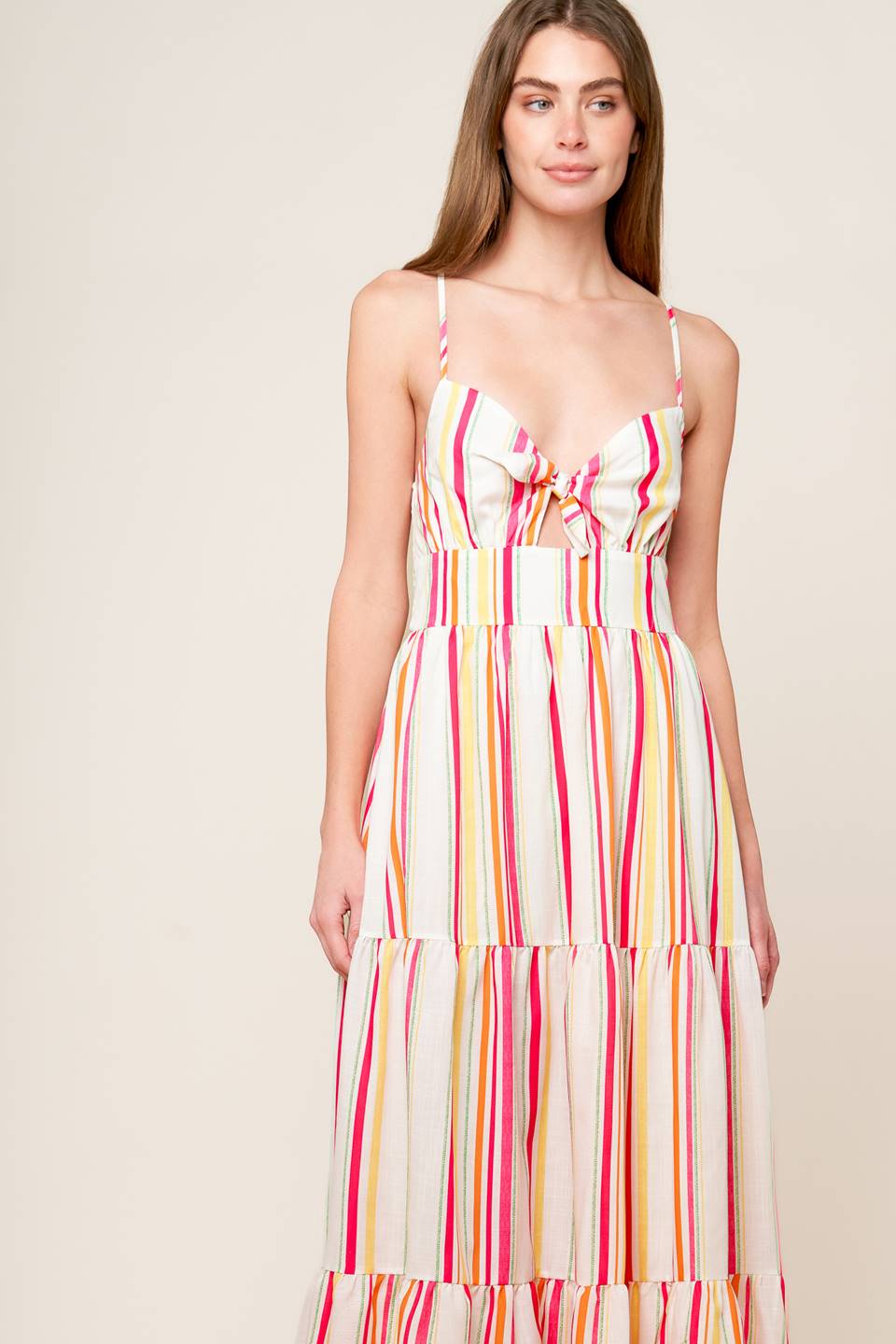 A striped woven maxi dress featuring cami bodice with center front tie and cut out, wide waistband, tiered skirt and smocked back bodice.