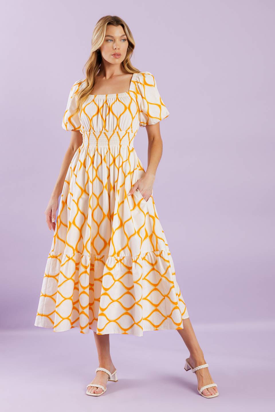 A printed woven midi dress featuring square neckline, short puff sleeves, smocked waistband, full skirt and ruffled hemline