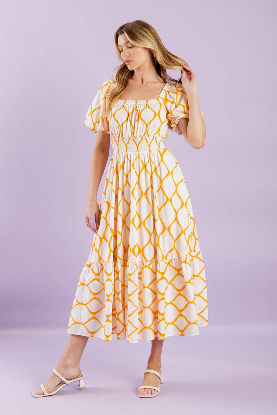 A printed woven midi dress featuring square neckline, short puff sleeves, smocked waistband, full skirt and ruffled hemline