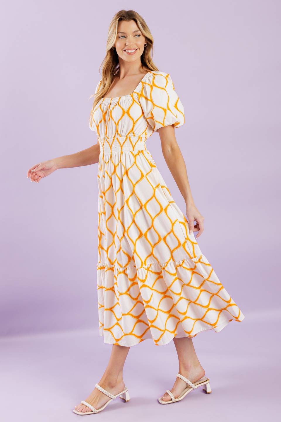 A printed woven midi dress featuring square neckline, short puff sleeves, smocked waistband, full skirt and ruffled hemline