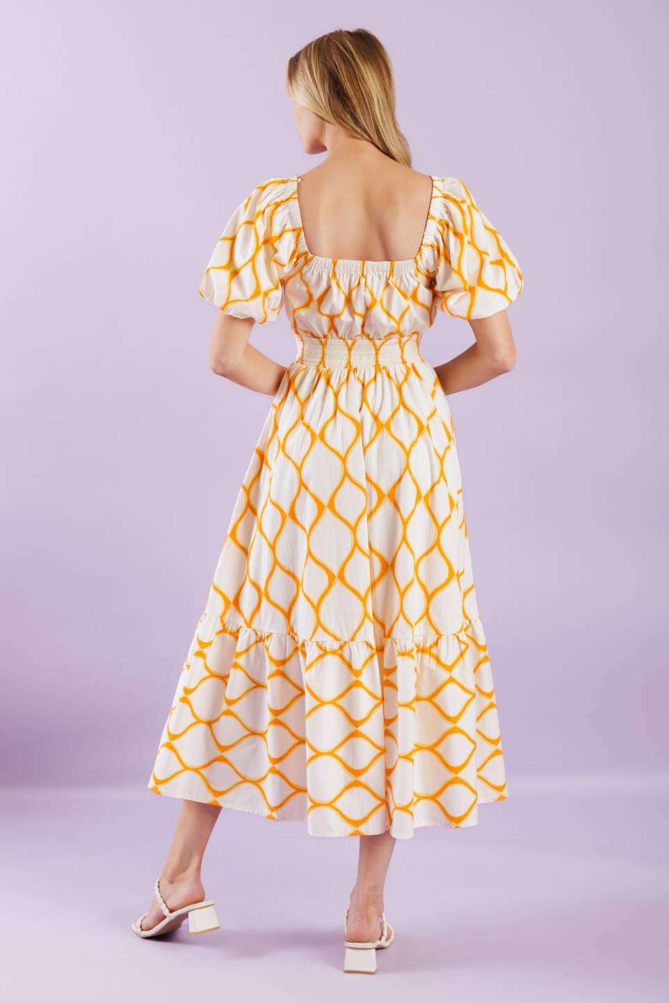 A printed woven midi dress featuring square neckline, short puff sleeves, smocked waistband, full skirt and ruffled hemline