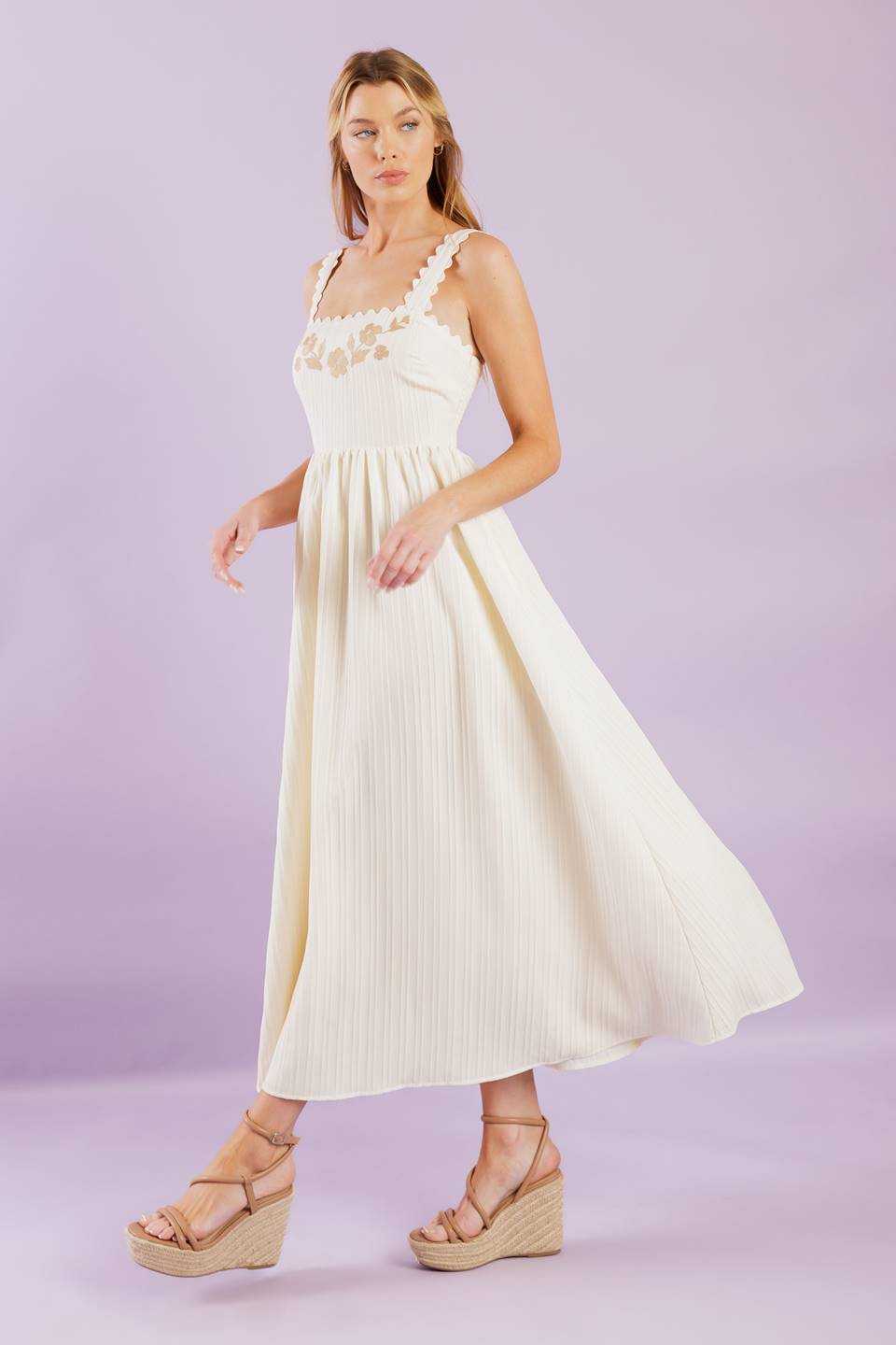 A solid woven midi dress featuring ric rac trimmed straight neckline and straps, embroidered bodice and smocked back bodice.