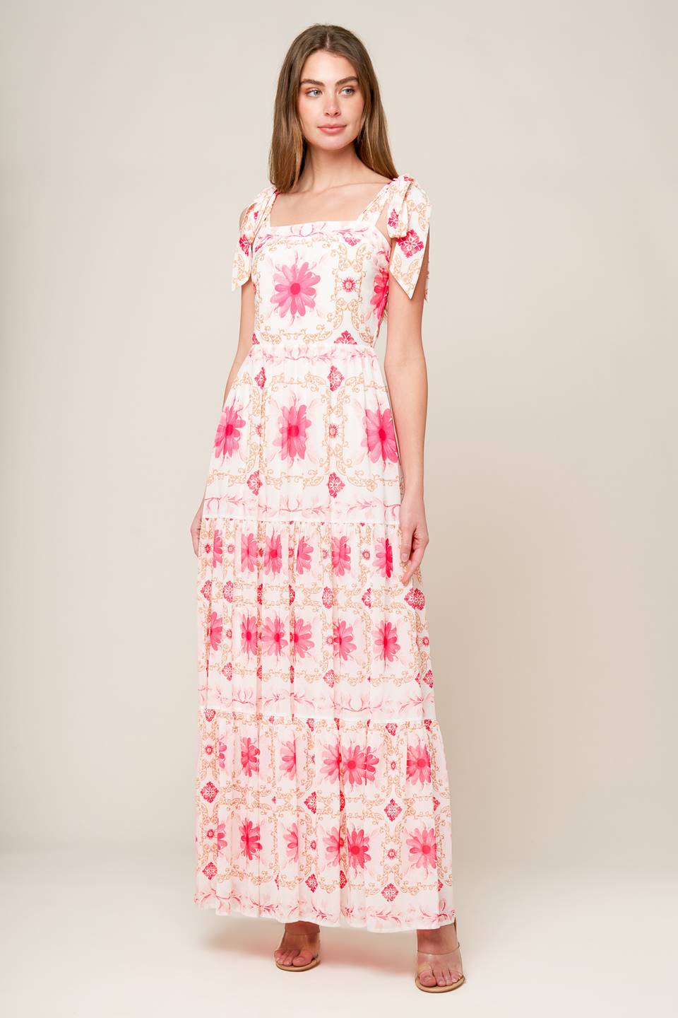 A printed woven maxi dress featuring straight neckline, shoulder ties, tiered skirt and back zipper closure.