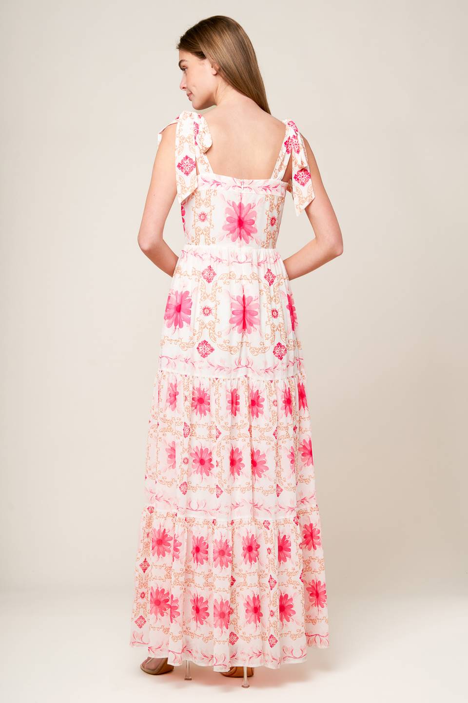 A printed woven maxi dress featuring straight neckline, shoulder ties, tiered skirt and back zipper closure.