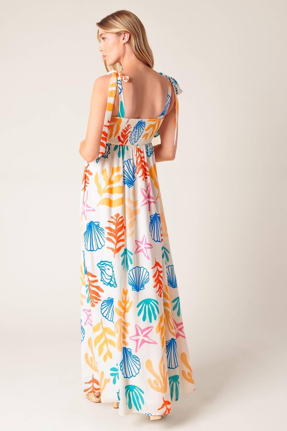 A printed woven maxi dress featuring straight neckline with ribbon edge, shoulder ties and smocked back bodice.