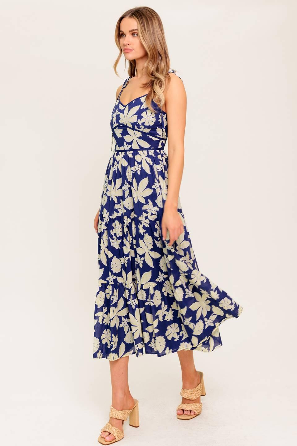 A printed woven midi dress featuring sweetheart neckline, shoulder tie, waist yoke, tiered skirt and back zipper closure.