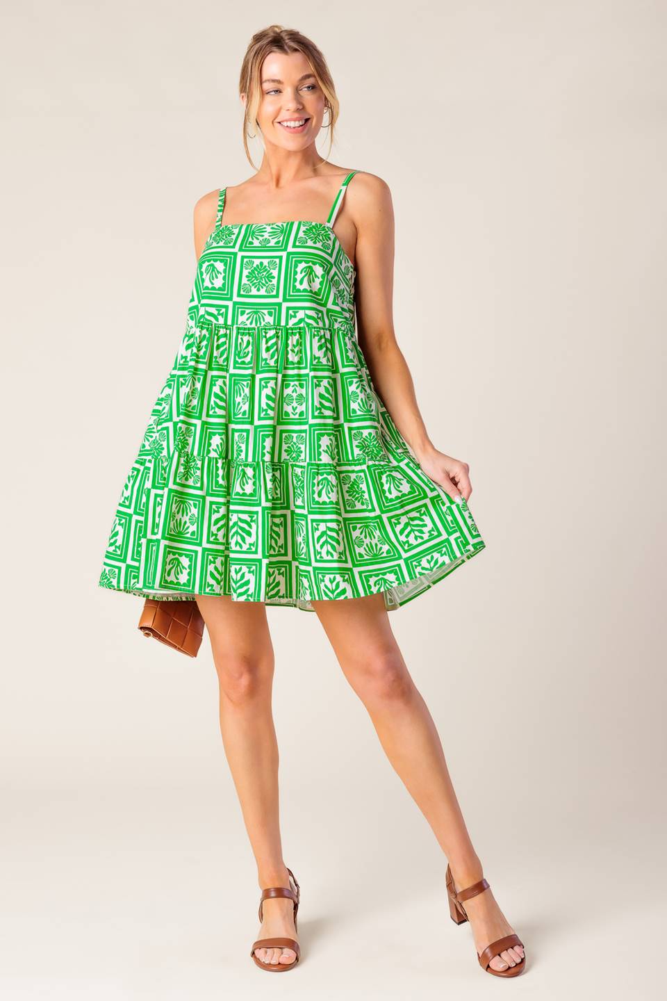 A white and green printed woven mini dress featuring straight neckline, straps and tiered body