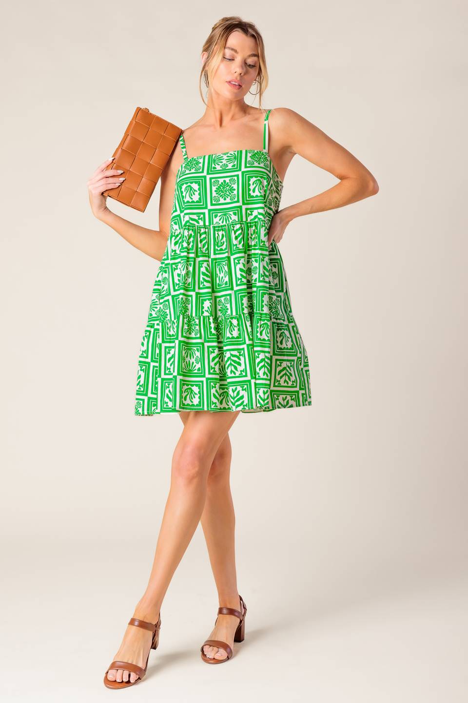 A white and green printed woven mini dress featuring straight neckline, straps and tiered body