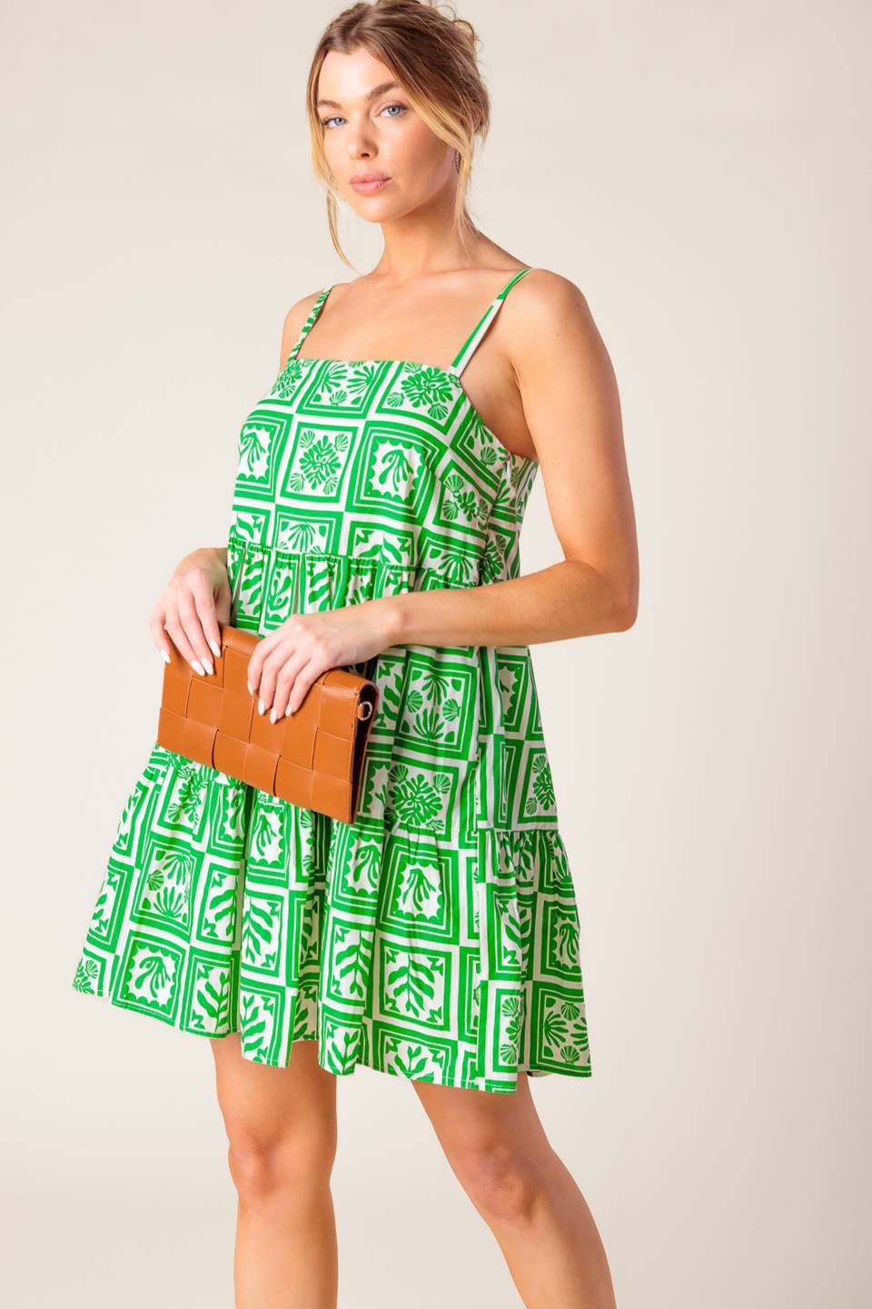 A white and green printed woven mini dress featuring straight neckline, straps and tiered body