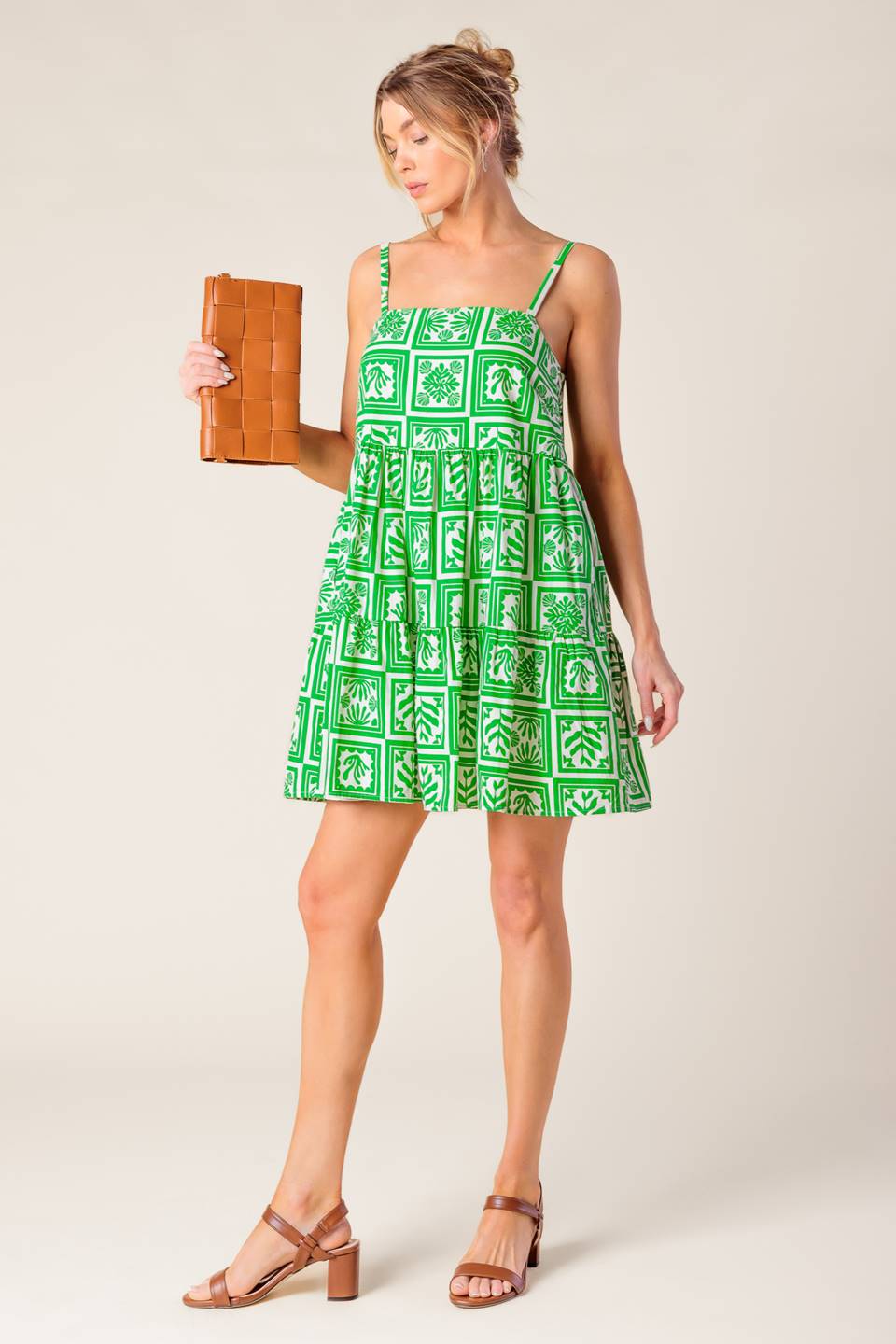 A white and green printed woven mini dress featuring straight neckline, straps and tiered body