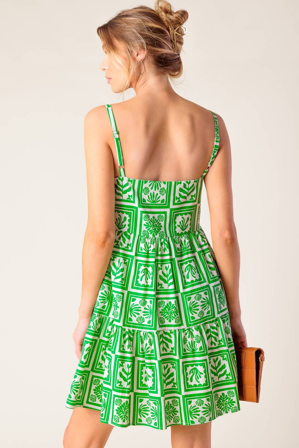 A white and green printed woven mini dress featuring straight neckline, straps and tiered body