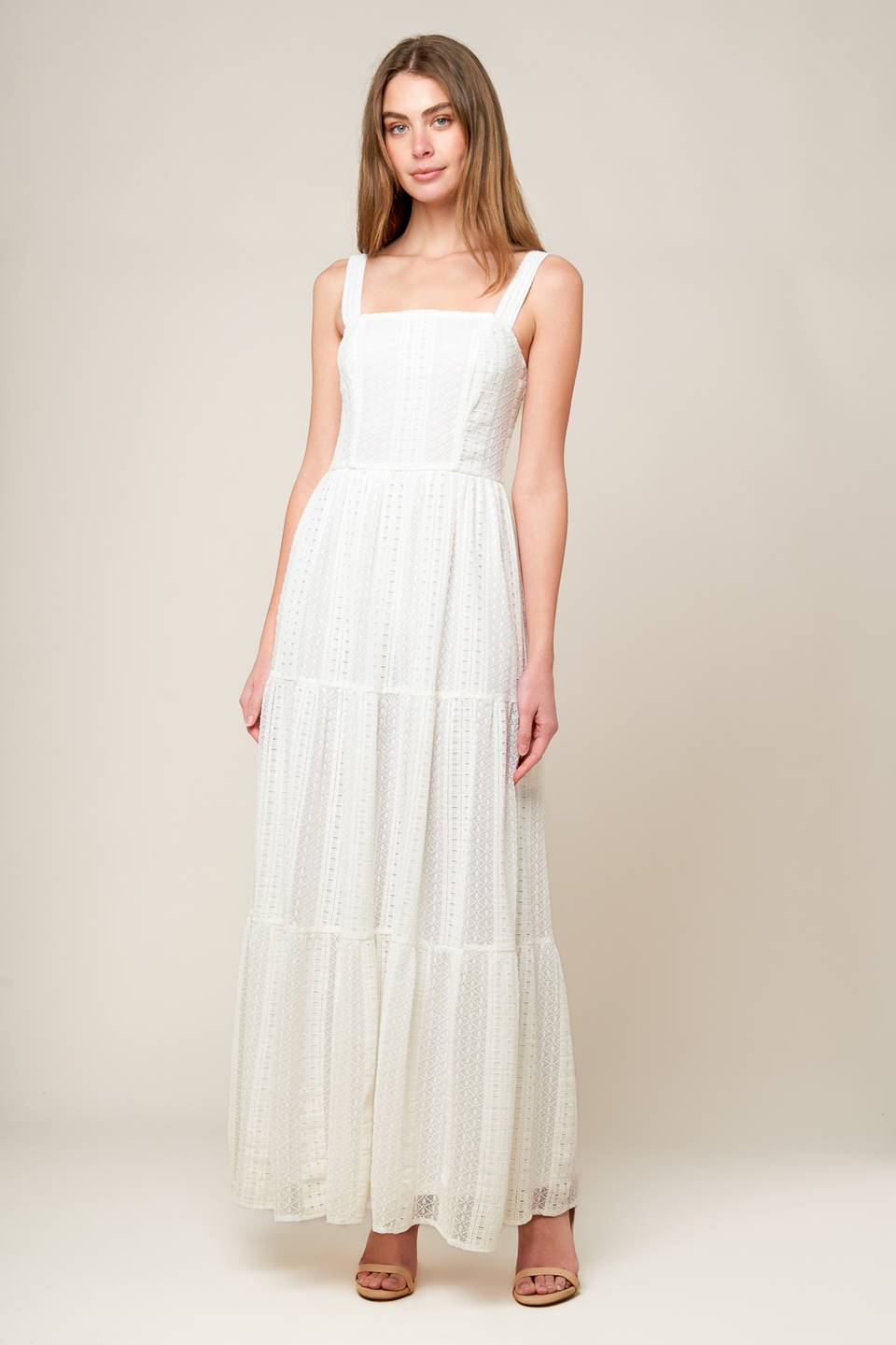 A white woven lace maxi dress featuring straight neckline, straps, tiered skirt and back zipper closure.