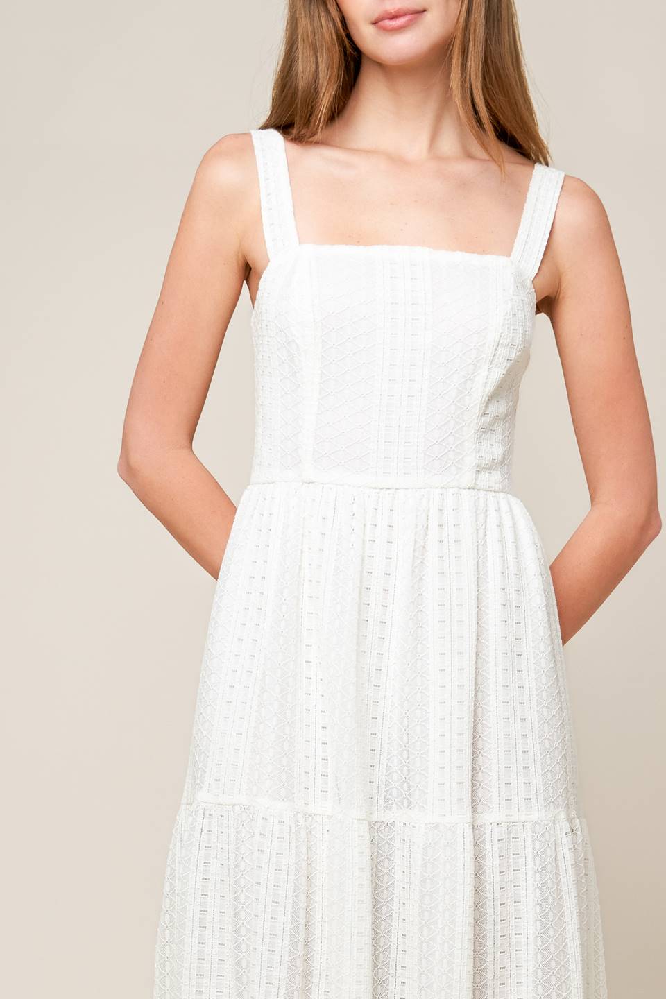 A white woven lace maxi dress featuring straight neckline, straps, tiered skirt and back zipper closure.