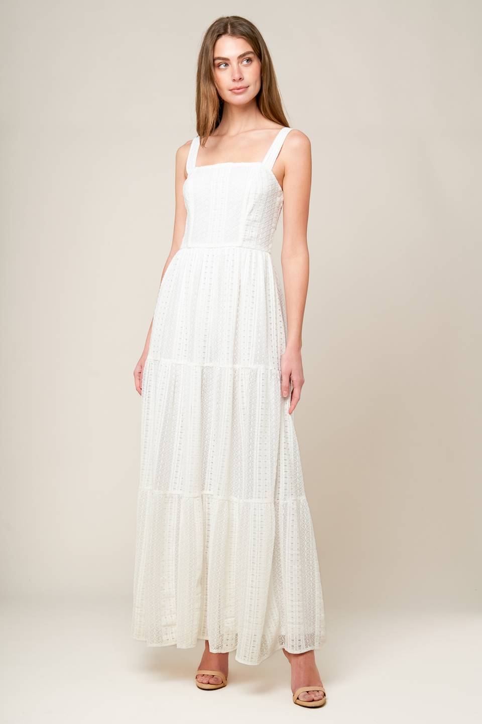 A white woven lace maxi dress featuring straight neckline, straps, tiered skirt and back zipper closure.