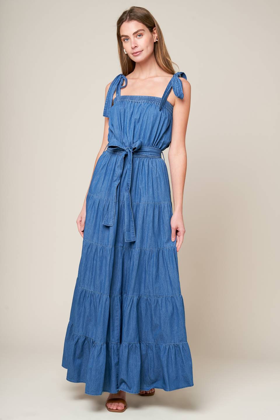 Revamp your vacation wardrobe with this chambray maxi dress! It boasts a straight neckline, shoulder ties, and an elasticized waist for a comfortable fit. The self sash tie and tiered skirt add a touch of elegance to this must-have piece.