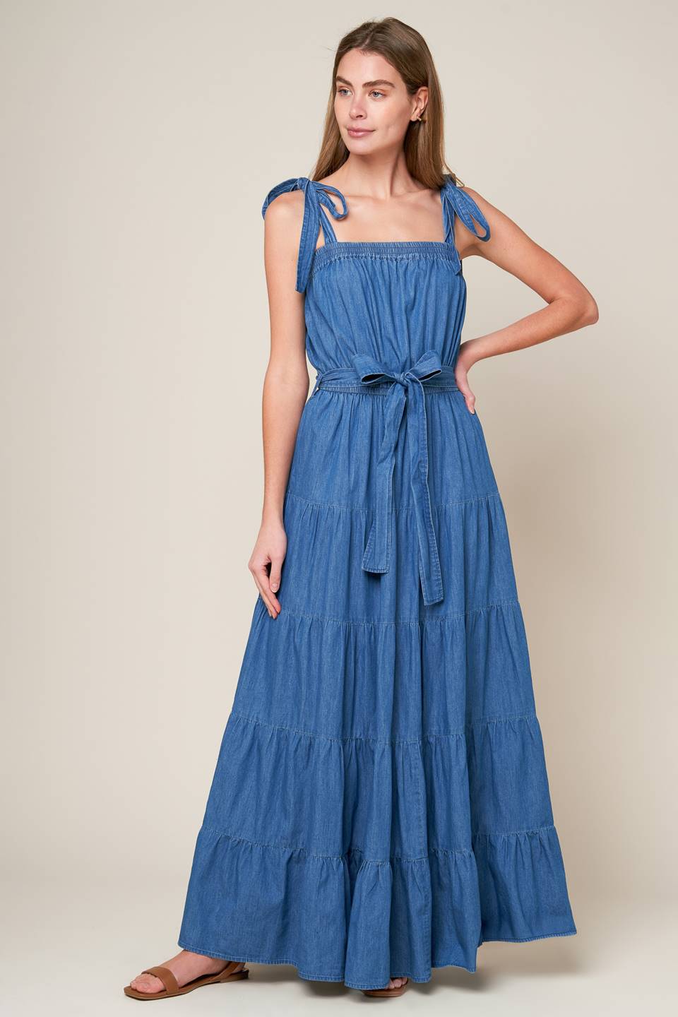 Revamp your vacation wardrobe with this chambray maxi dress! It boasts a straight neckline, shoulder ties, and an elasticized waist for a comfortable fit. The self sash tie and tiered skirt add a touch of elegance to this must-have piece.