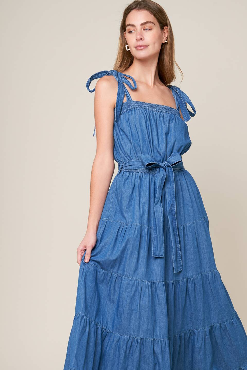 Revamp your vacation wardrobe with this chambray maxi dress! It boasts a straight neckline, shoulder ties, and an elasticized waist for a comfortable fit. The self sash tie and tiered skirt add a touch of elegance to this must-have piece.