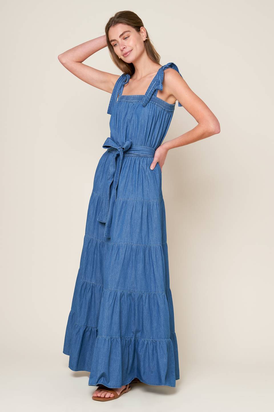 Revamp your vacation wardrobe with this chambray maxi dress! It boasts a straight neckline, shoulder ties, and an elasticized waist for a comfortable fit. The self sash tie and tiered skirt add a touch of elegance to this must-have piece.