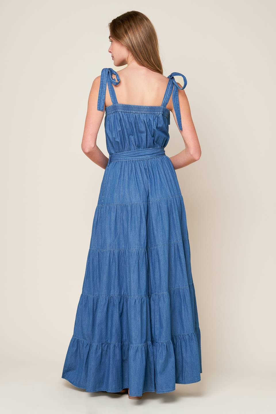 Revamp your vacation wardrobe with this chambray maxi dress! It boasts a straight neckline, shoulder ties, and an elasticized waist for a comfortable fit. The self sash tie and tiered skirt add a touch of elegance to this must-have piece.