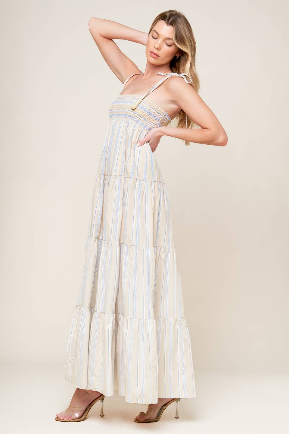 A striped woven maxi dress featuring smocked bodice, shoulder straps with tassel and tiered skirt.