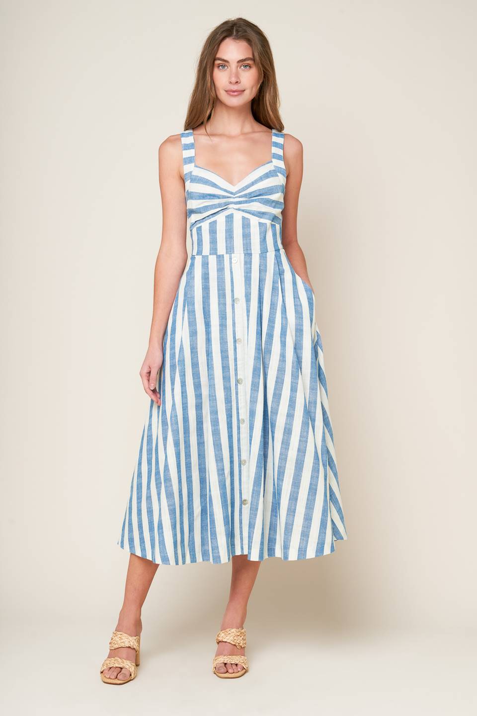 A white and blue striped woven midi dress featuring V neckline, cinched bust center, waist yoke and back zipper closure.