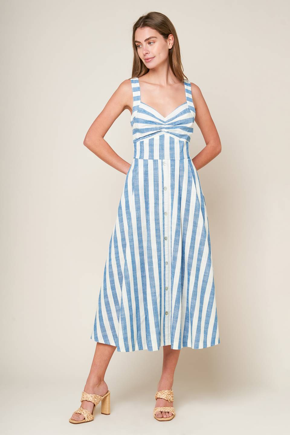 A white and blue striped woven midi dress featuring V neckline, cinched bust center, waist yoke and back zipper closure.