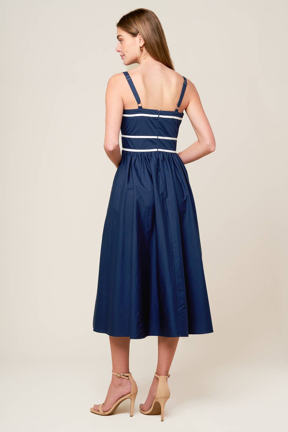 A solid navy woven midi dress featuring straight neckline, straps, full skirt and back zipper closure.