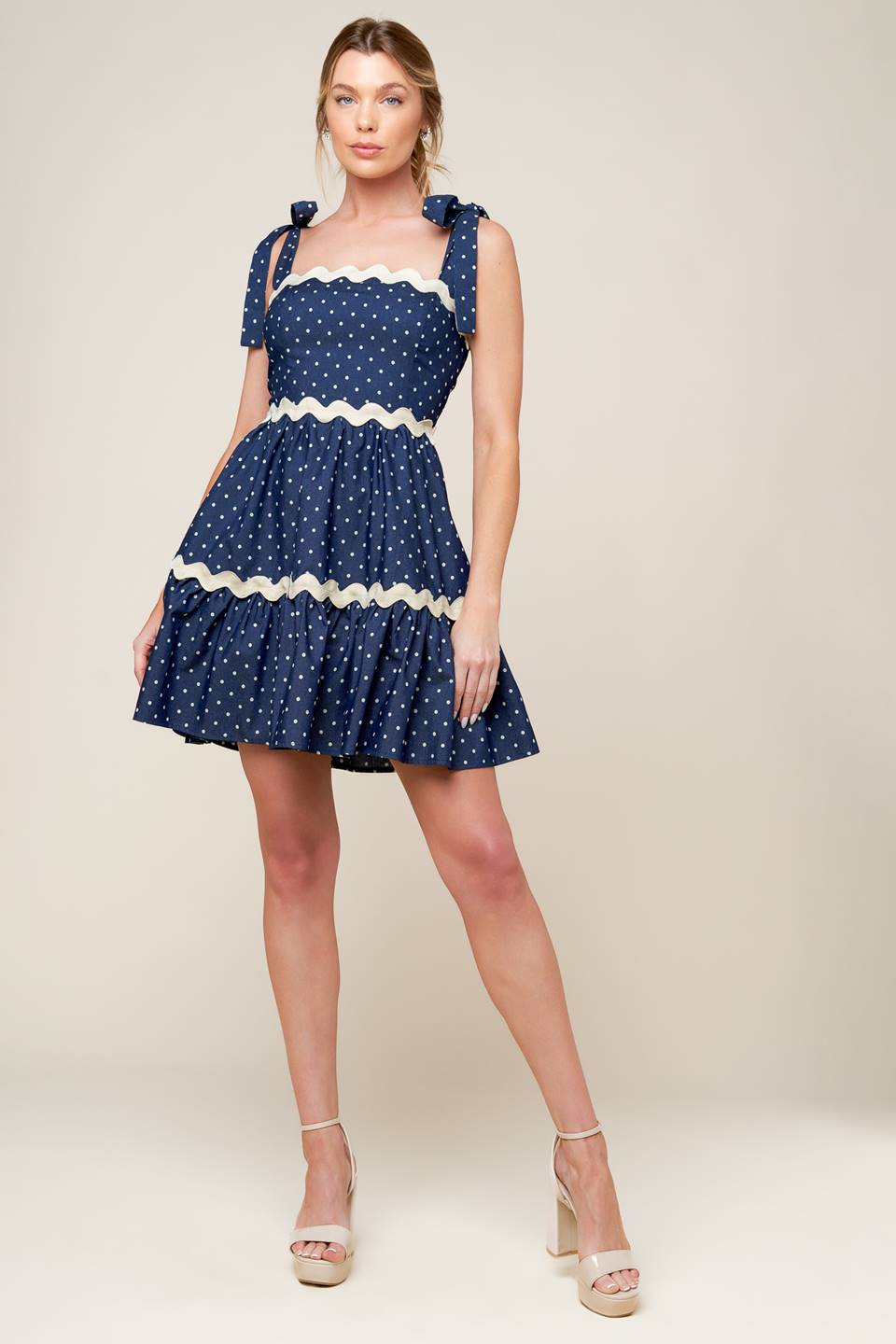 A dotted woven mini dress featuring straight neckline, ric rac ribbon detail, shoulder ties and smocked back bodice.