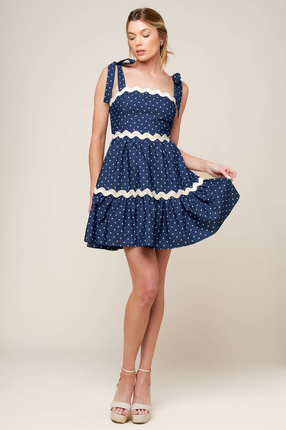 A dotted woven mini dress featuring straight neckline, ric rac ribbon detail, shoulder ties and smocked back bodice.