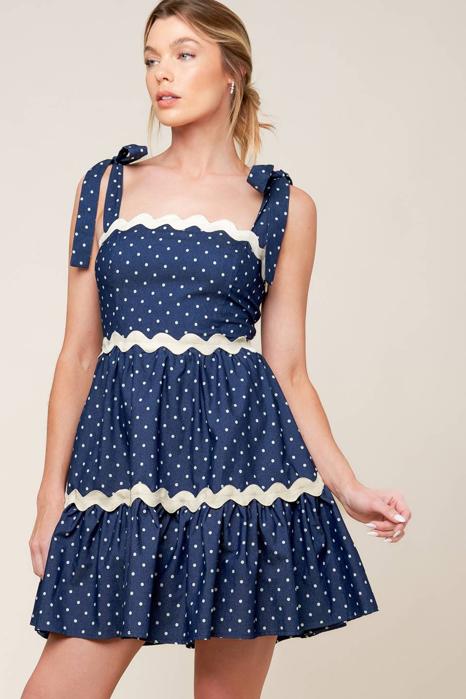 A dotted woven mini dress featuring straight neckline, ric rac ribbon detail, shoulder ties and smocked back bodice.