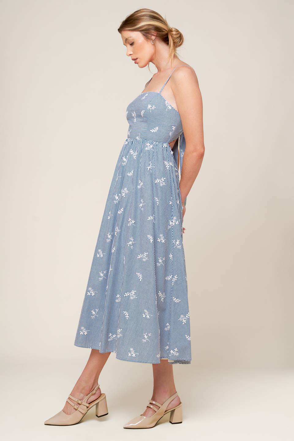 A blue and white striped woven midi dress featuring straight neckline, straps, full skirt, bare back with tie detail featuring white embroidery.