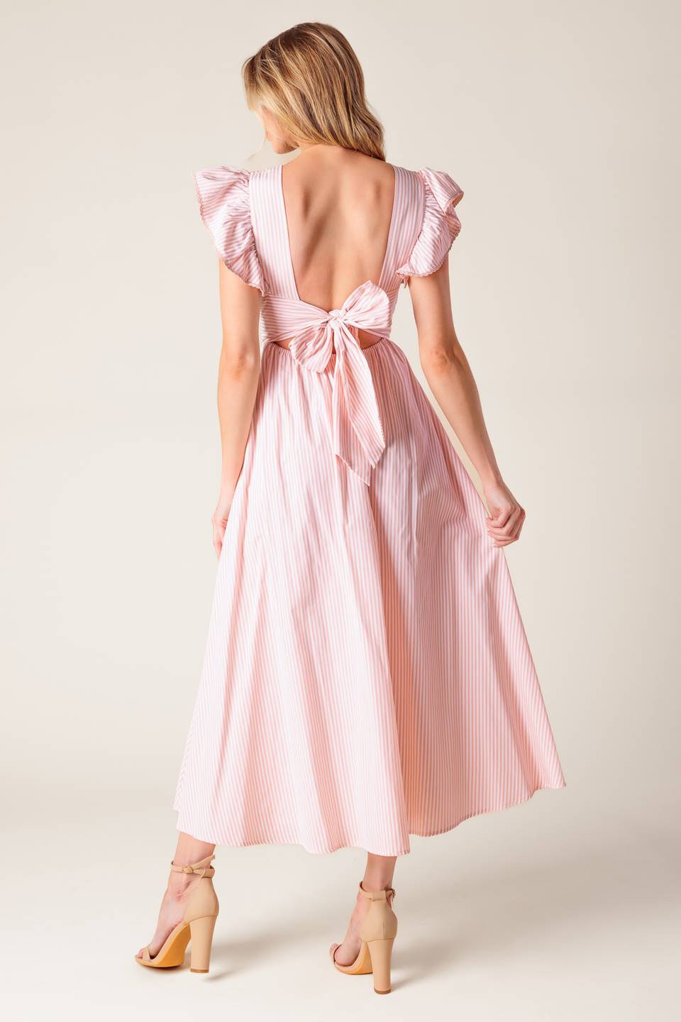 A pink and white striped woven midi dress featuring V neckline, ruffled sleeve, waist yoke, full skirt and bare back with tie detail.