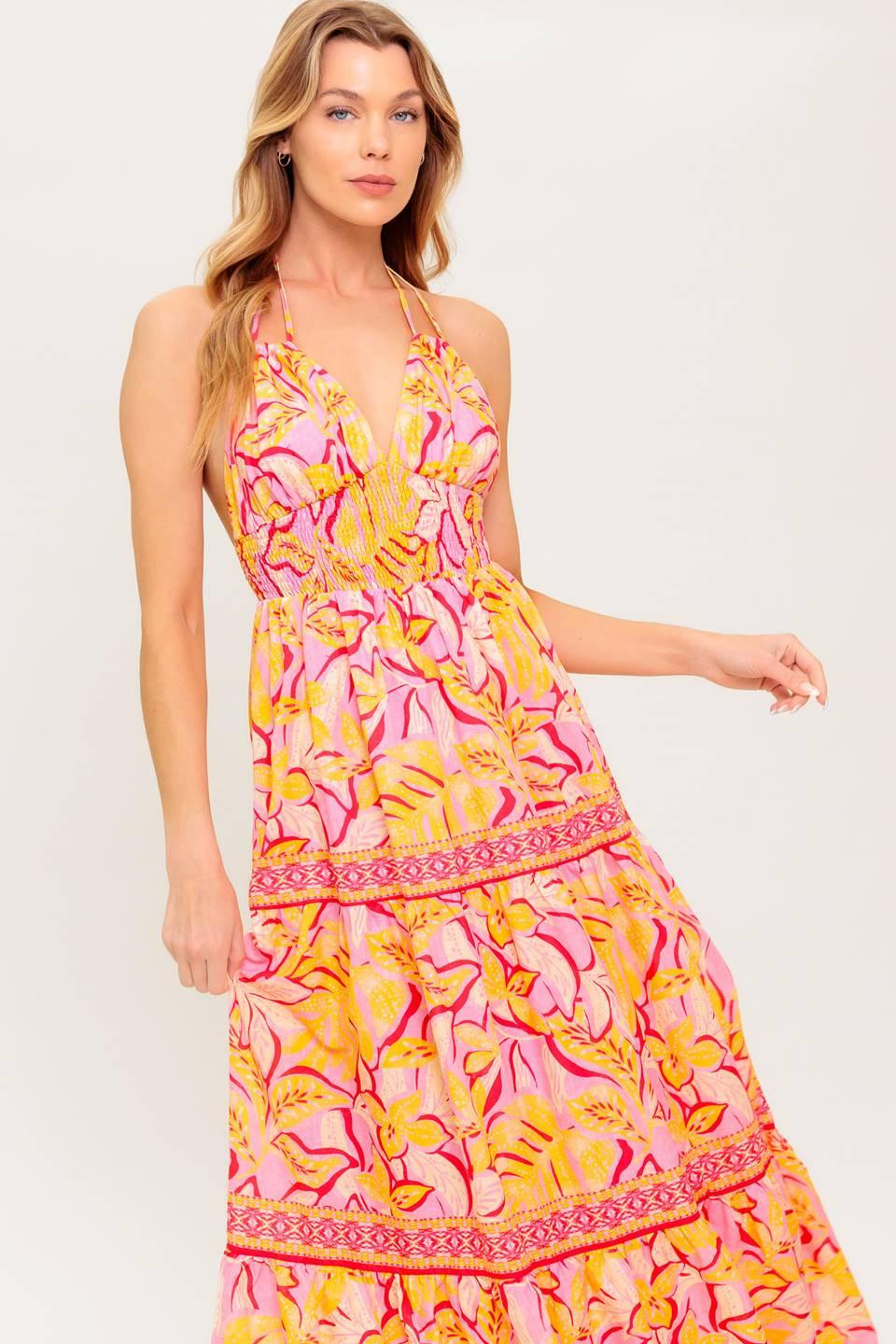 A printed woven maxi dress featuring cami top with halter tie, smocked waist yoke, tiered skirt and bare back