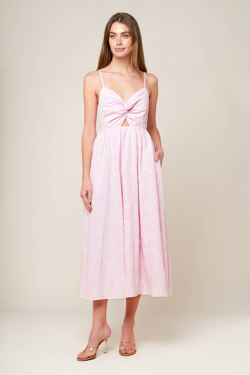 A pink textured woven midi dress featuring sweetheart neckline, front twist with cut out, straps and smocked back bodice.