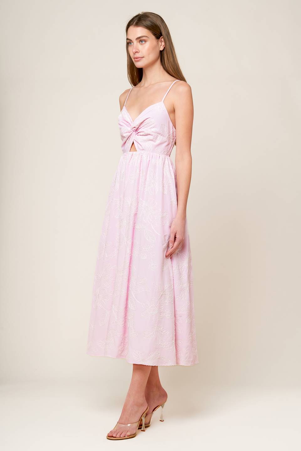 A pink textured woven midi dress featuring sweetheart neckline, front twist with cut out, straps and smocked back bodice.