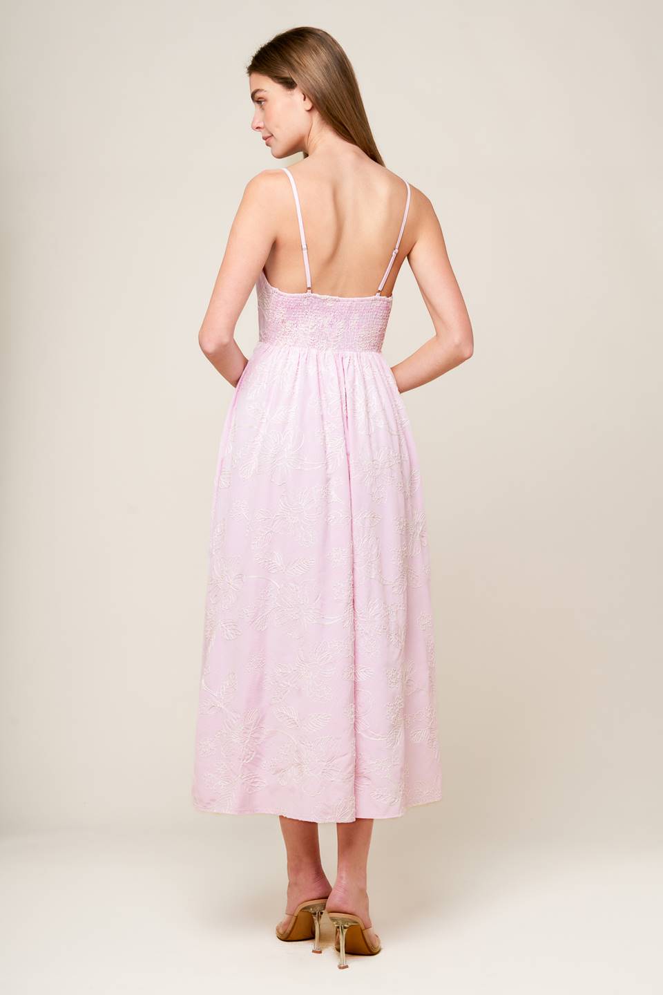 A pink textured woven midi dress featuring sweetheart neckline, front twist with cut out, straps and smocked back bodice.