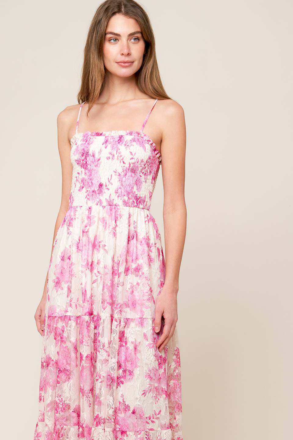 A pink and ivory, floral printed woven lace maxi dress featuring straight neckline with ruffled edge, straps, smocked bodice and tiered skirt.