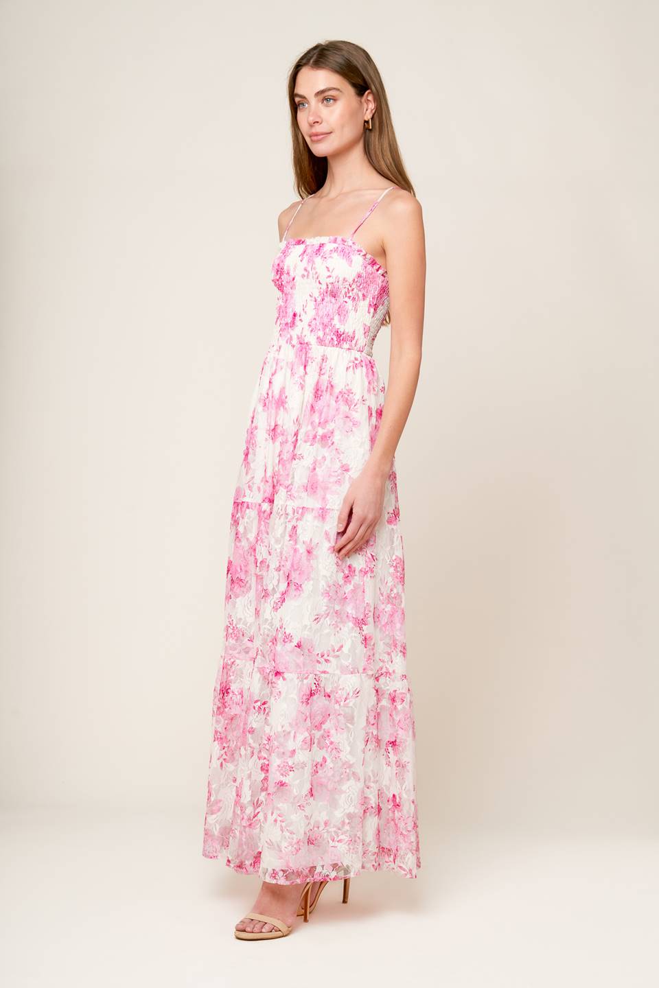 A pink and ivory, floral printed woven lace maxi dress featuring straight neckline with ruffled edge, straps, smocked bodice and tiered skirt.