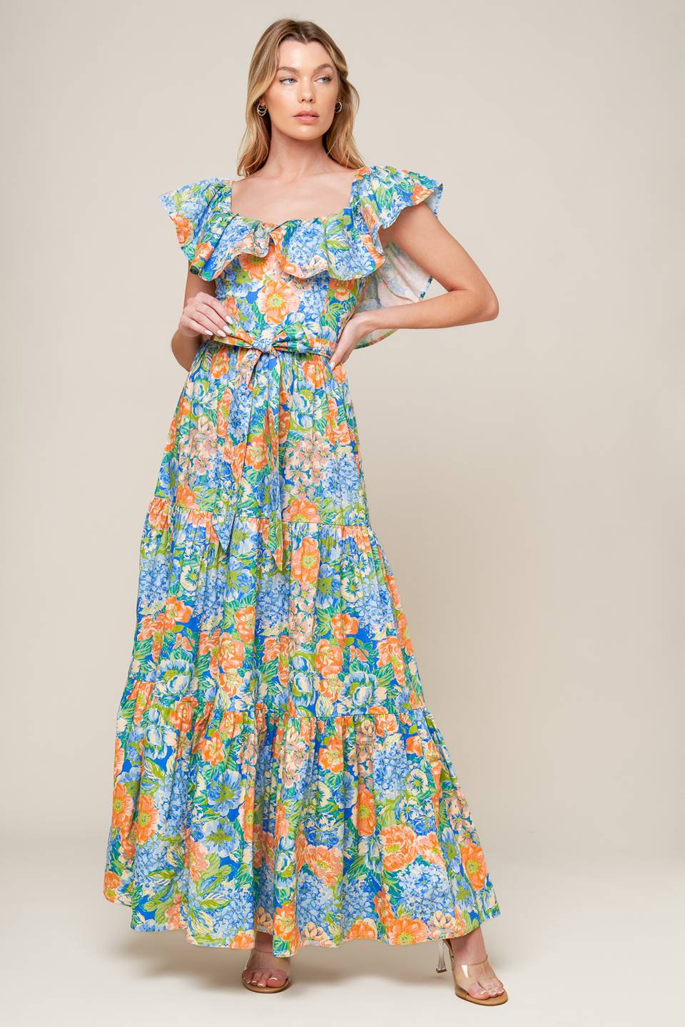 A printed woven maxi dress featuring off shoulder neckline, flounce, self sash tie, tiered skirt and smocked back bodice.