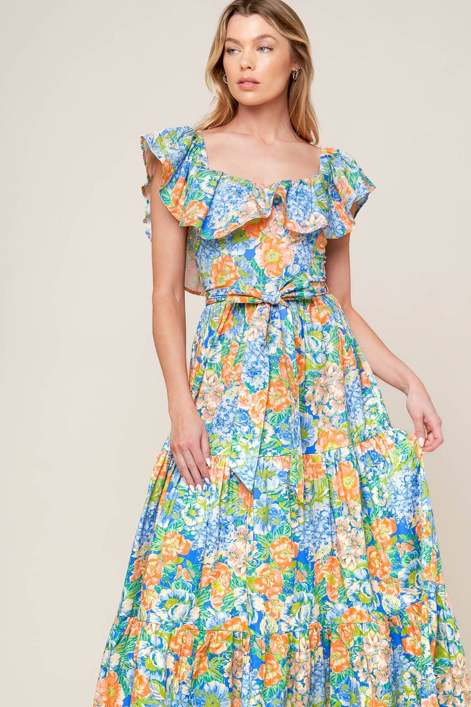 A printed woven maxi dress featuring off shoulder neckline, flounce, self sash tie, tiered skirt and smocked back bodice.