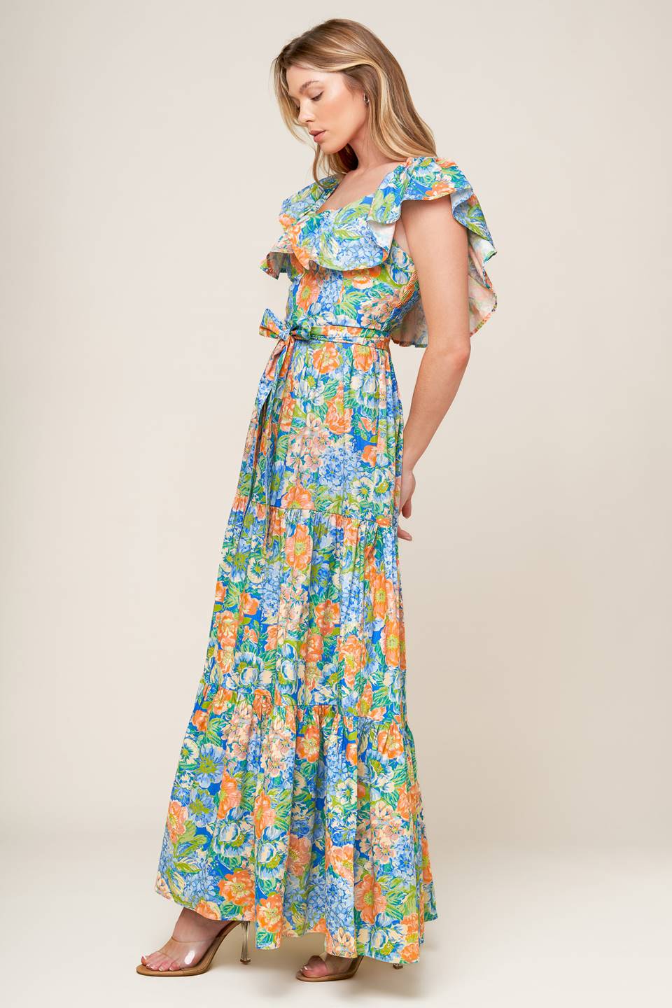 A printed woven maxi dress featuring off shoulder neckline, flounce, self sash tie, tiered skirt and smocked back bodice.