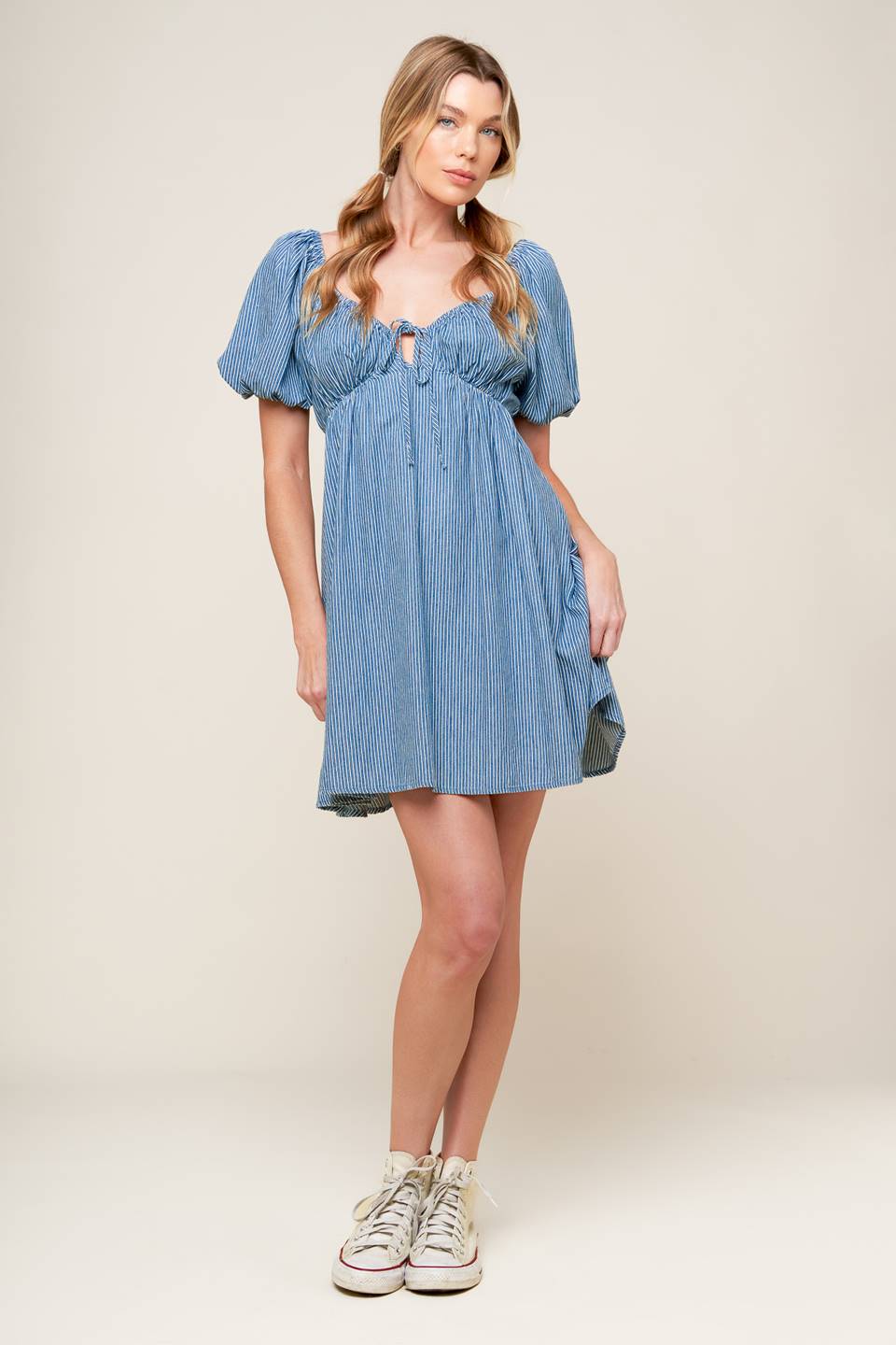 A striped blue woven mini dress featuring sweetheart neckline with front tie, short puff sleeve and elasticized empire.