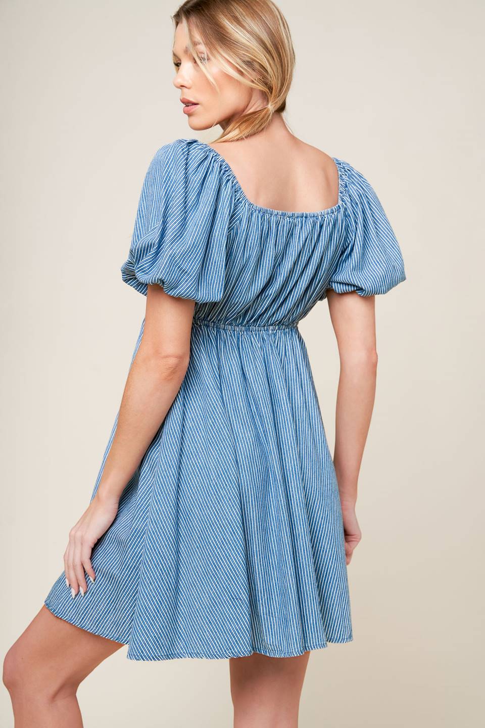 A striped blue woven mini dress featuring sweetheart neckline with front tie, short puff sleeve and elasticized empire.