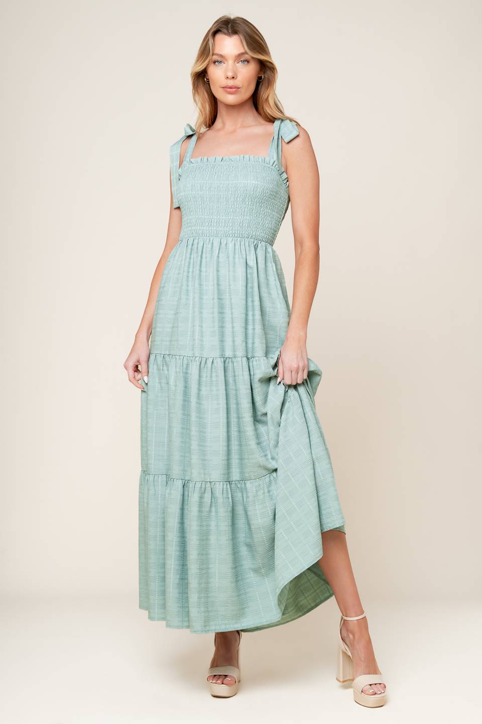 A textured solid woven maxi dress featuring straight neckline with ruffled edge, shoulder tie, smocked bodice and tiered skirt