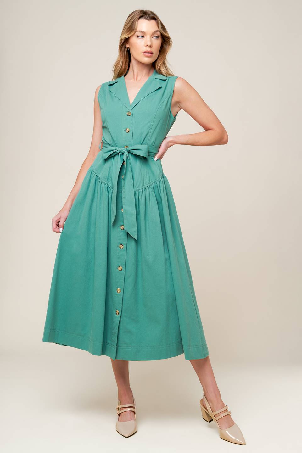 A solid woven midi dress featuring collar, front button down, sleeveless, self sash tie and full skirt.