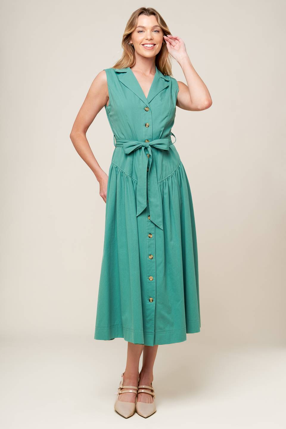 A solid woven midi dress featuring collar, front button down, sleeveless, self sash tie and full skirt.