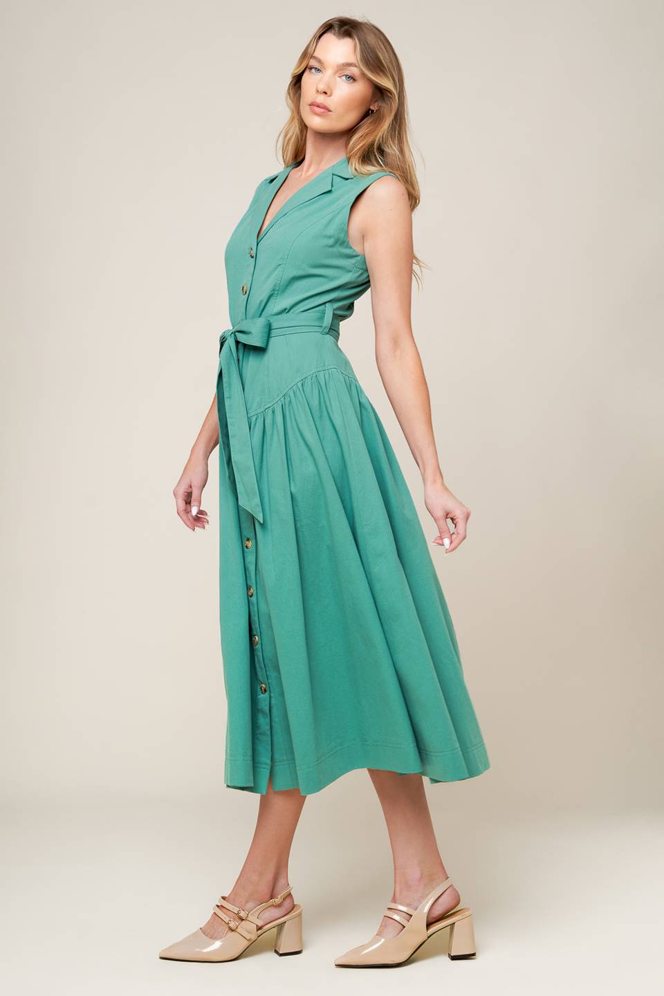 A solid woven midi dress featuring collar, front button down, sleeveless, self sash tie and full skirt.