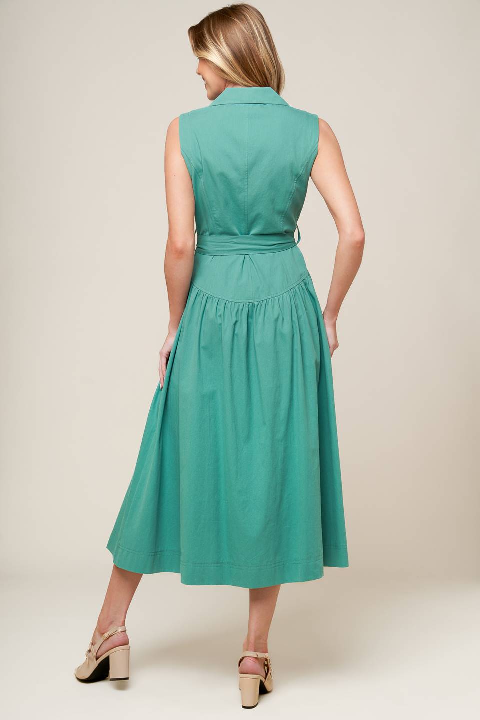 A solid woven midi dress featuring collar, front button down, sleeveless, self sash tie and full skirt.