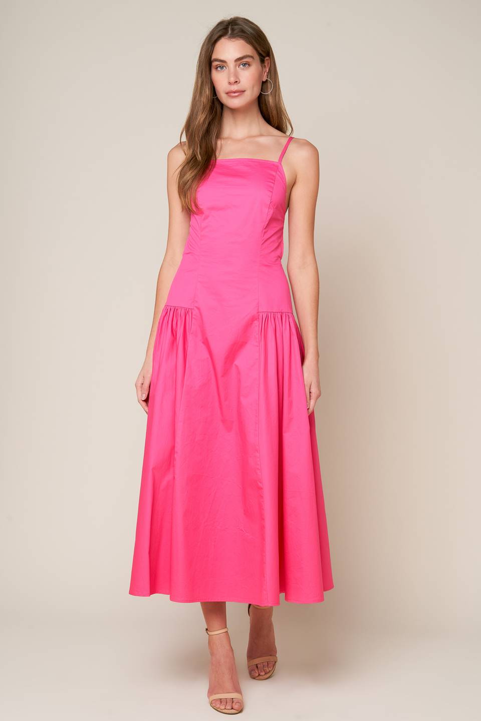 A midi dress with a solid woven fabric, sweetheart neckline, straps, and a full skirt with shirring on the sides. The back is open with a strap and zipper closure.